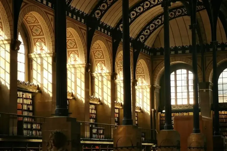 Salle de lecture de la bibliothèque Sainte-Geneviève, avec ses arcs en fer, ses colonnes de fonte fines, ses rayonnages et ses lampes de travail